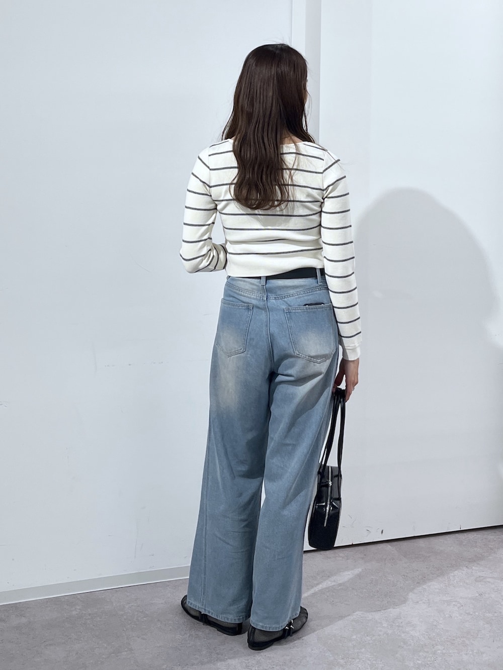 ブラック系のショルダーバッグ、ホワイト系のニット/セーター、ブルー系のデニムパンツを着用したレディースの冬コーディネートの8枚目の写真