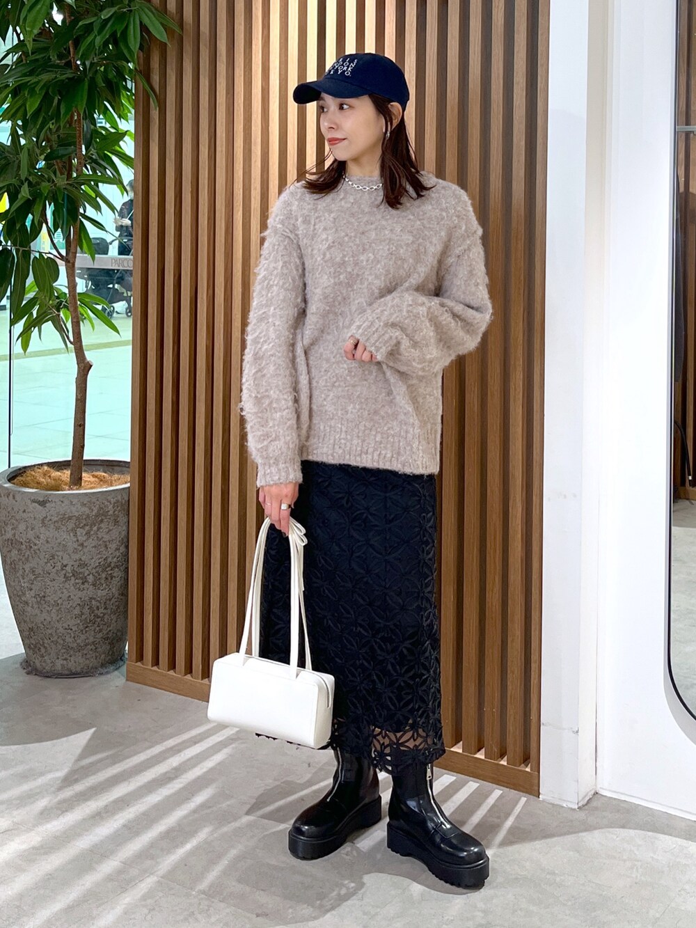 ホワイト系のショルダーバッグ、ベージュ系のニット/セーター、ブラック系のスカートを着用したレディースの冬コーディネートの3枚目の写真