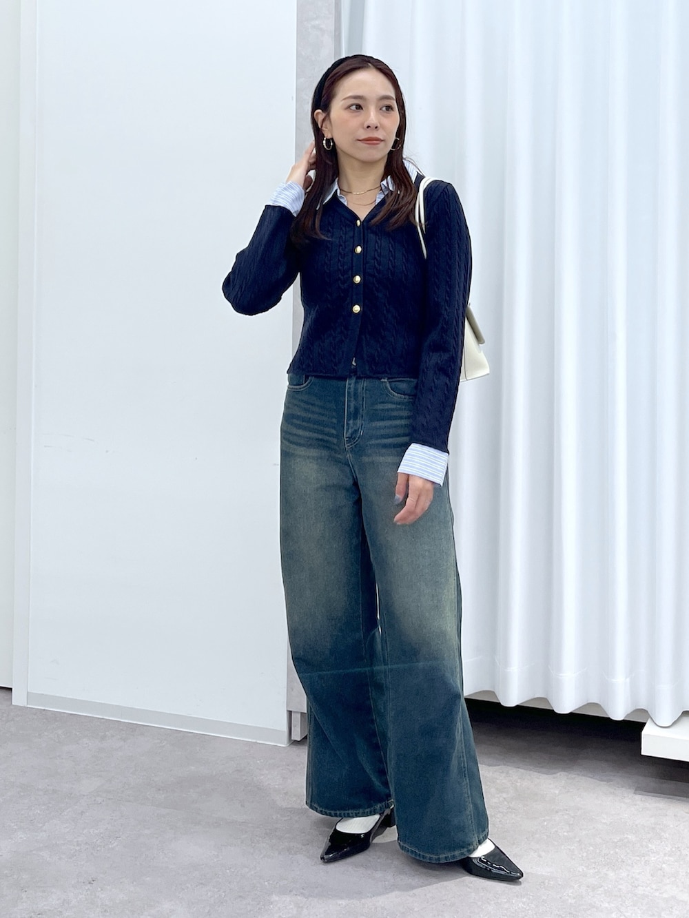 ブラック系のパンプス、ブルー系のニット/セーター、ホワイト系のショルダーバッグを着用したレディースの冬コーディネートの2枚目の写真