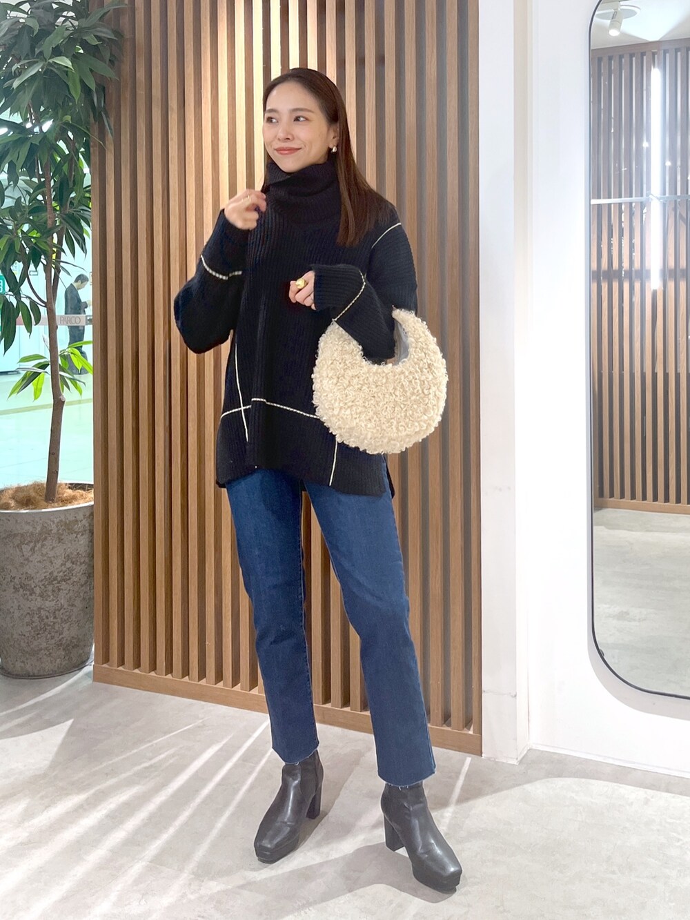 ブラック系のニット/セーター、ベージュ系のショルダーバッグ、ブルー系のデニムパンツを着用したレディースの秋コーディネートの3枚目の写真