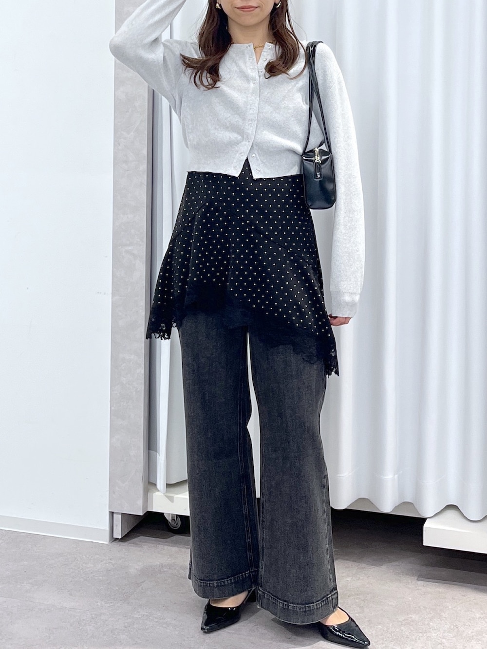 ブラック系のワンピース、ブラック系のデニムパンツ、ブラック系のショルダーバッグを着用したレディースの春コーディネートの7枚目の写真