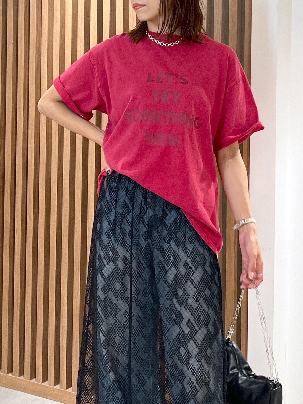 レッド系のTシャツ/カットソー、ブラック系のハンドバッグ、ブルー系のデニムパンツを着用したレディースの夏コーディネートの6枚目の写真