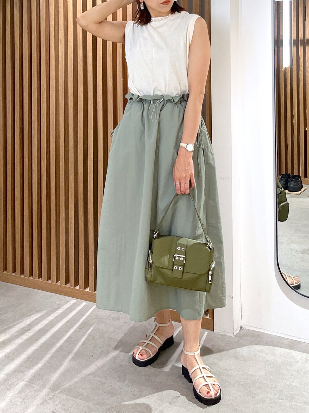 グリーン系のショルダーバッグ、グリーン系のワンピース、ホワイト系のサンダルを着用したレディースの夏コーディネートの6枚目の写真