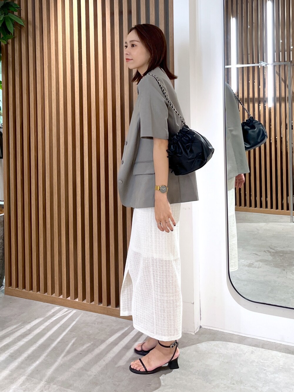 グレー系のノーカラージャケット、ブラック系のショルダーバッグ、ホワイト系のタンクトップを着用したレディースの夏コーディネートの7枚目の写真