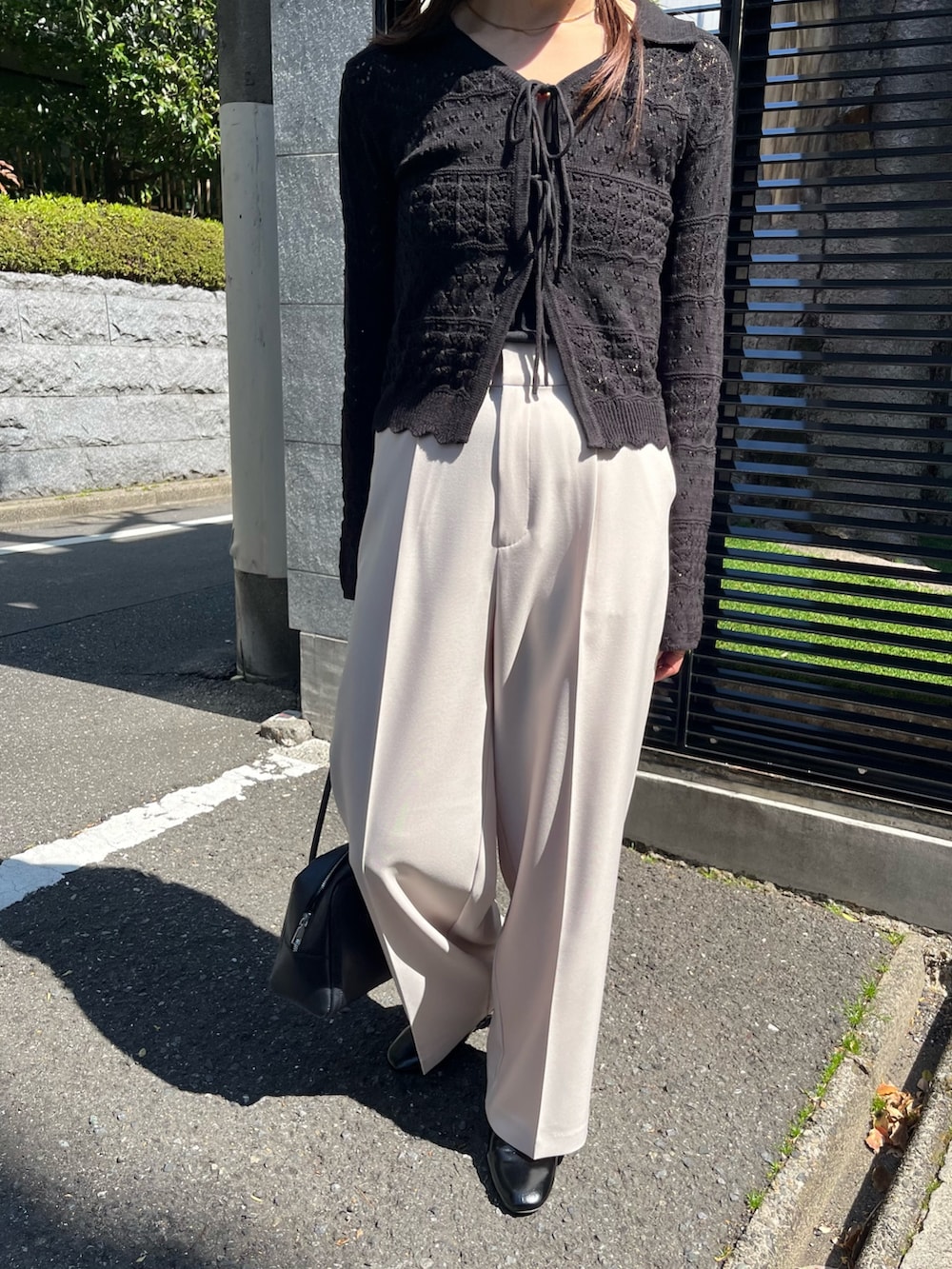 ブラック系のニット/セーター、ベージュ系のスラックス、ブラック系のパンプスを着用したレディースの春コーディネートの7枚目の写真