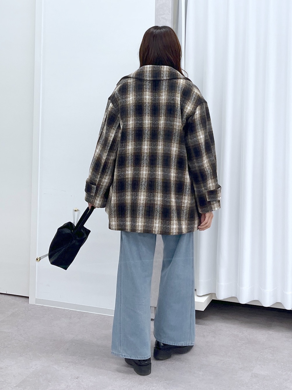 ブラック系のショルダーバッグ、ブルー系のデニムパンツ、ブラック系のニット/セーターを着用したレディースの冬コーディネートの5枚目の写真