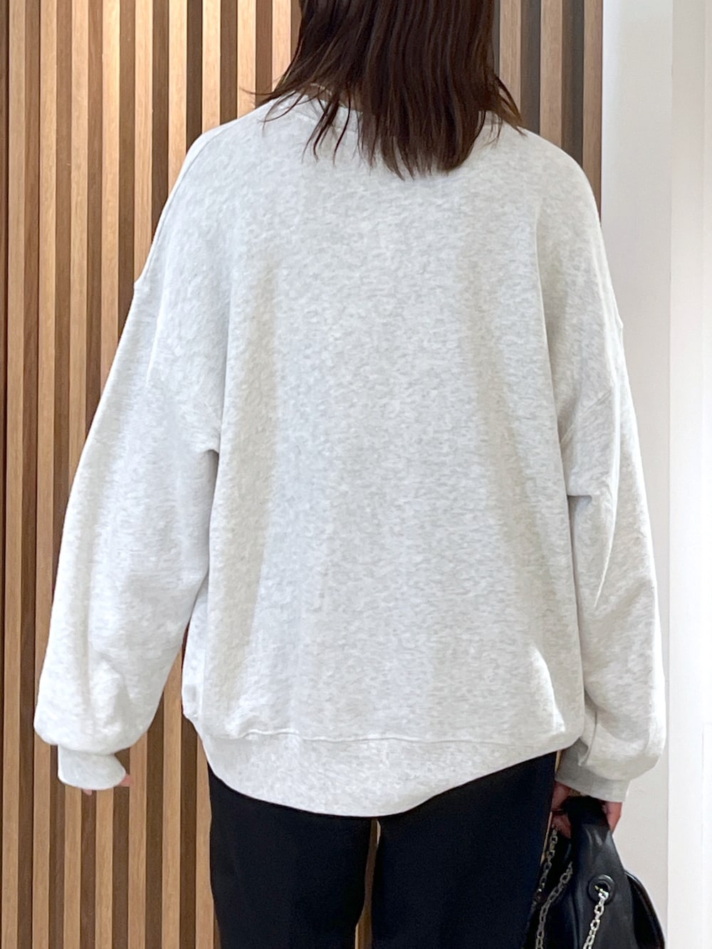 ホワイト系のスウェット、ブラック系のショルダーバッグ、ブラック系のスラックスを着用したレディースの秋コーディネートの7枚目の写真