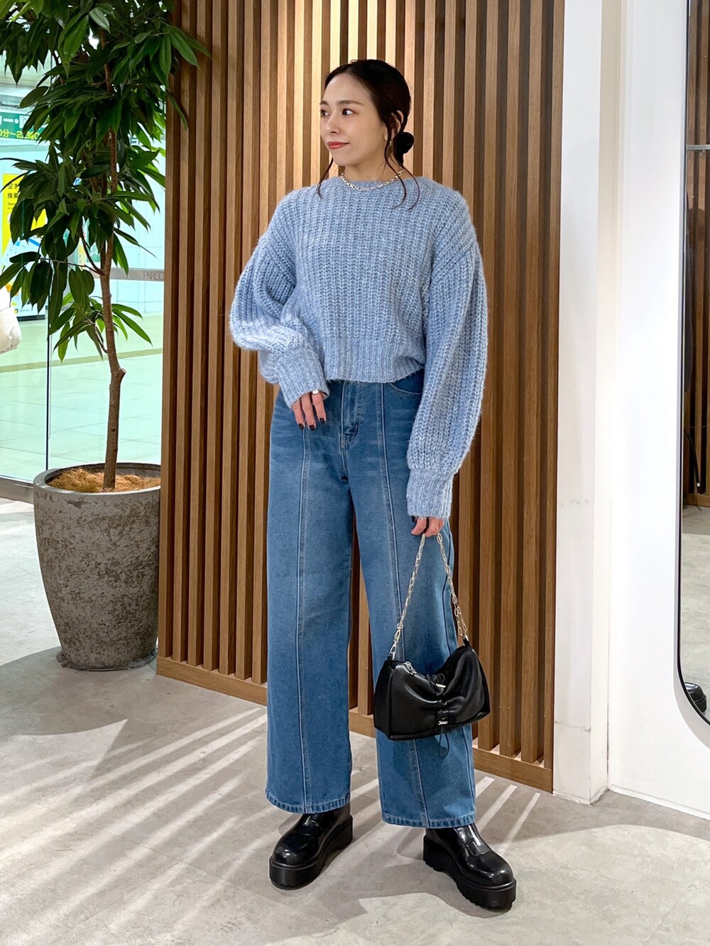 ブルー系のニット/セーター、ブルー系のデニムパンツ、ブラック系のハンドバッグを着用したレディースの冬コーディネートの2枚目の写真