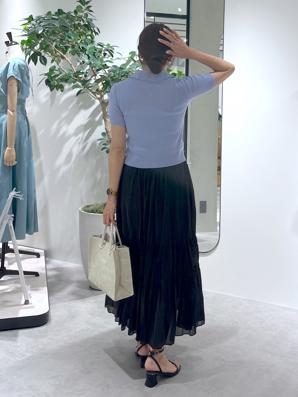 ホワイト系のトートバッグ、ブラック系のスカート、ブルー系のニット/セーターを着用したレディースの夏コーディネートの5枚目の写真