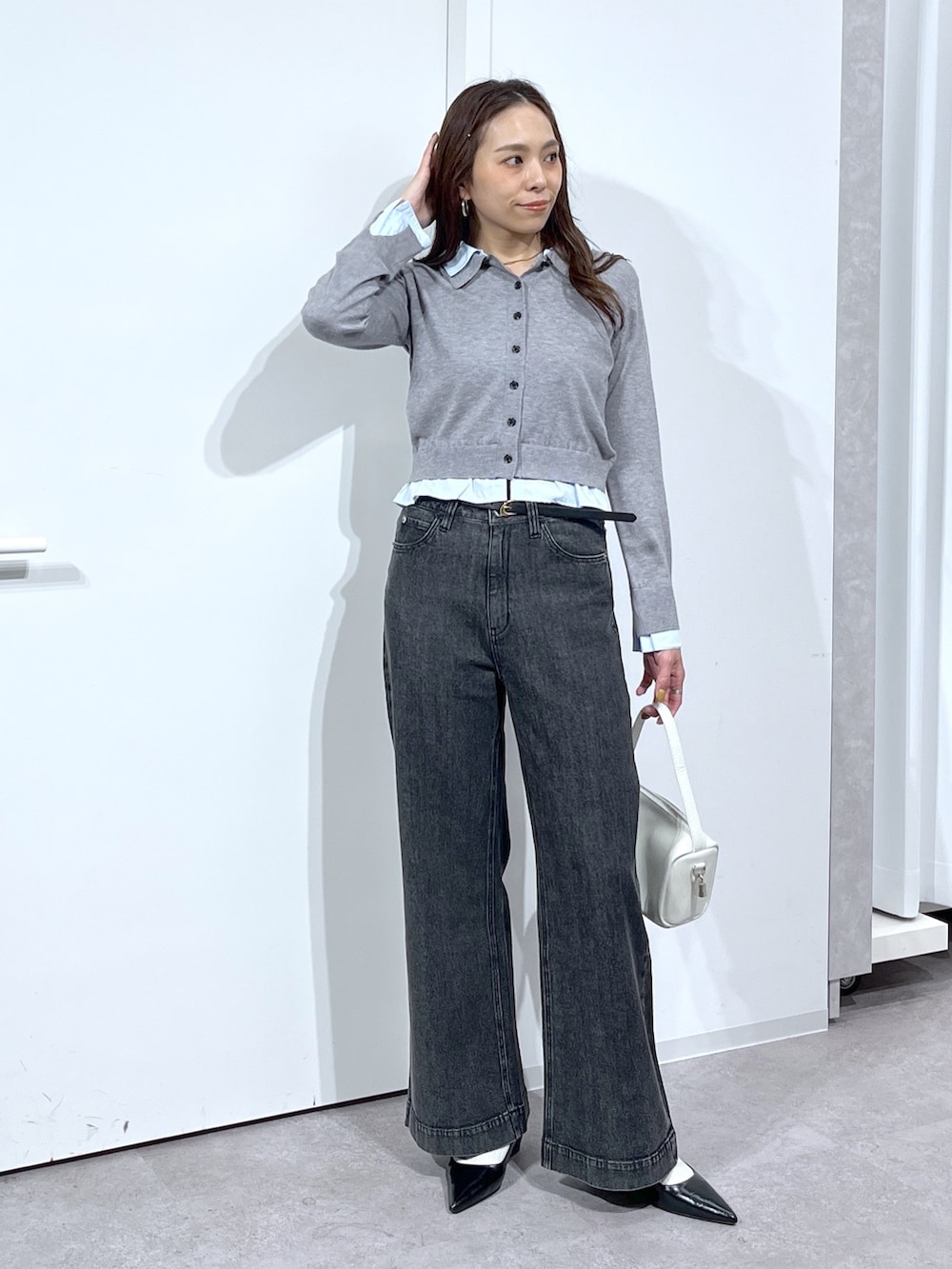 グレー系のニット/セーター、ホワイト系のハンドバッグ、ブラック系のデニムパンツを着用したレディースの春コーディネートの3枚目の写真