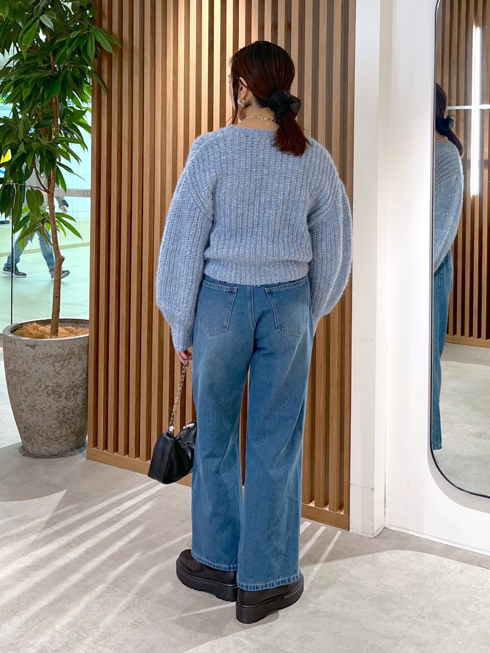 ブルー系のニット/セーター、ブルー系のデニムパンツ、ブラック系のハンドバッグを着用したレディースの冬コーディネートの6枚目の写真