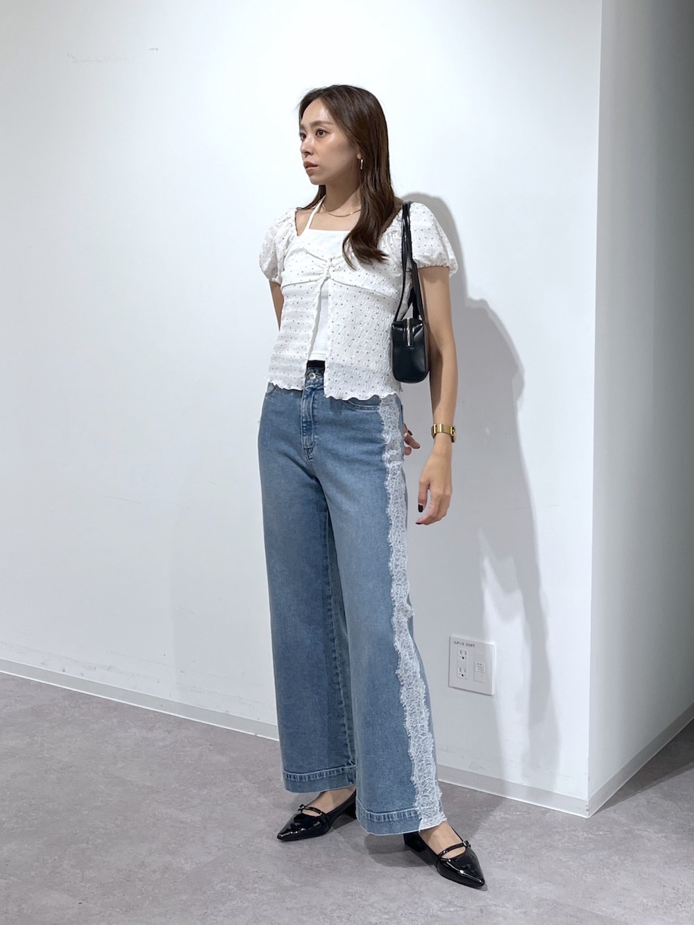 ブラック系のショルダーバッグ、ブラック系のパンプス、ブルー系のデニムパンツを着用したレディースの夏コーディネートの7枚目の写真