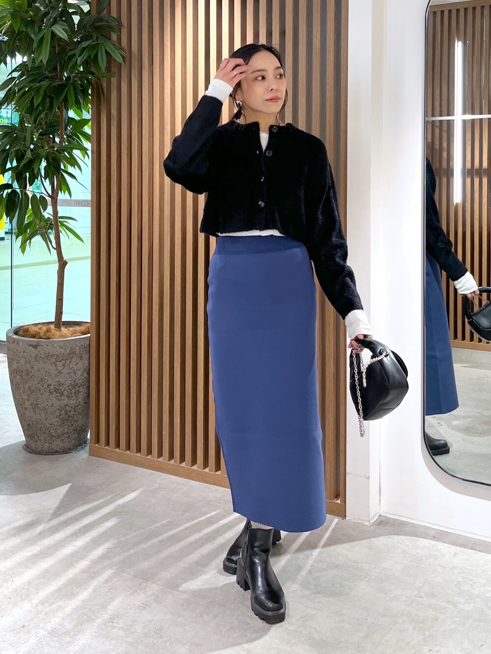 ブラック系のカーディガン/ボレロ、ブラック系のショルダーバッグ、ブルー系のスカートを着用したレディースの冬コーディネートの3枚目の写真