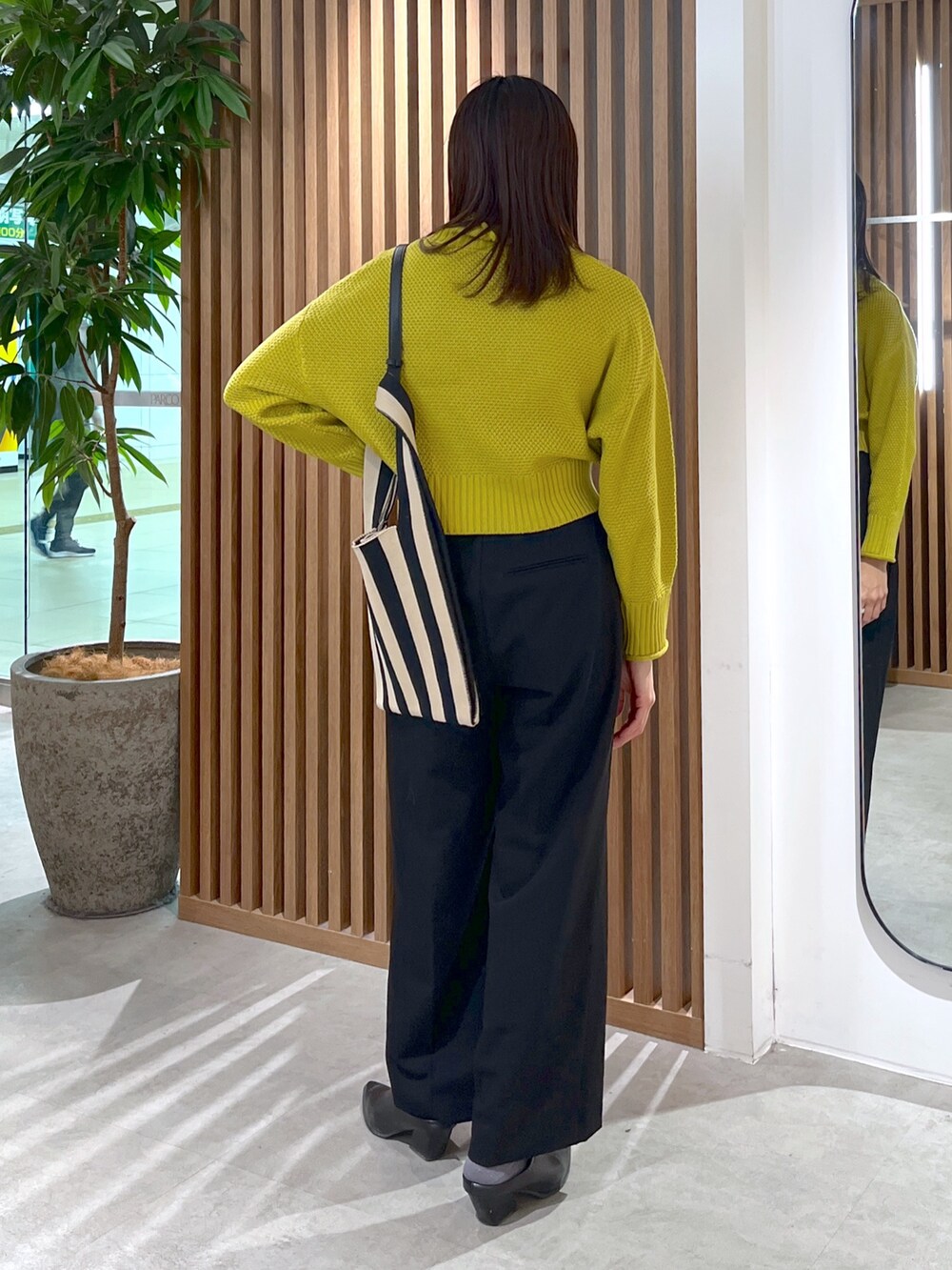 イエロー系のニット/セーター、ブラック系のスラックス、ブラック系のショルダーバッグを着用したレディースの冬コーディネートの5枚目の写真