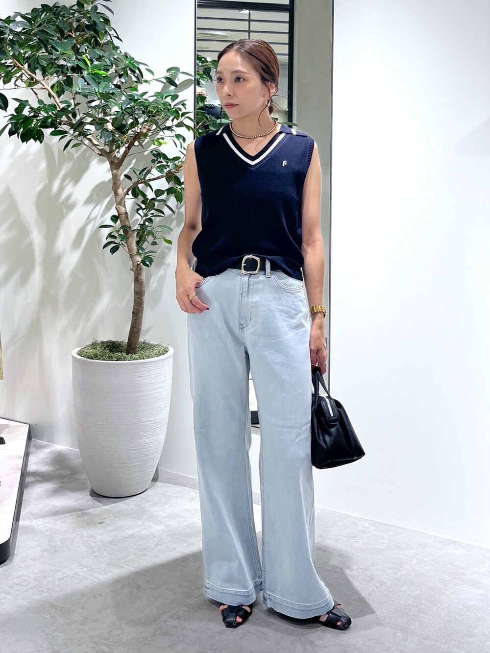 ブルー系のニット/セーター、ブルー系のデニムパンツ、ブラック系のショルダーバッグを着用したレディースの夏コーディネートの2枚目の写真