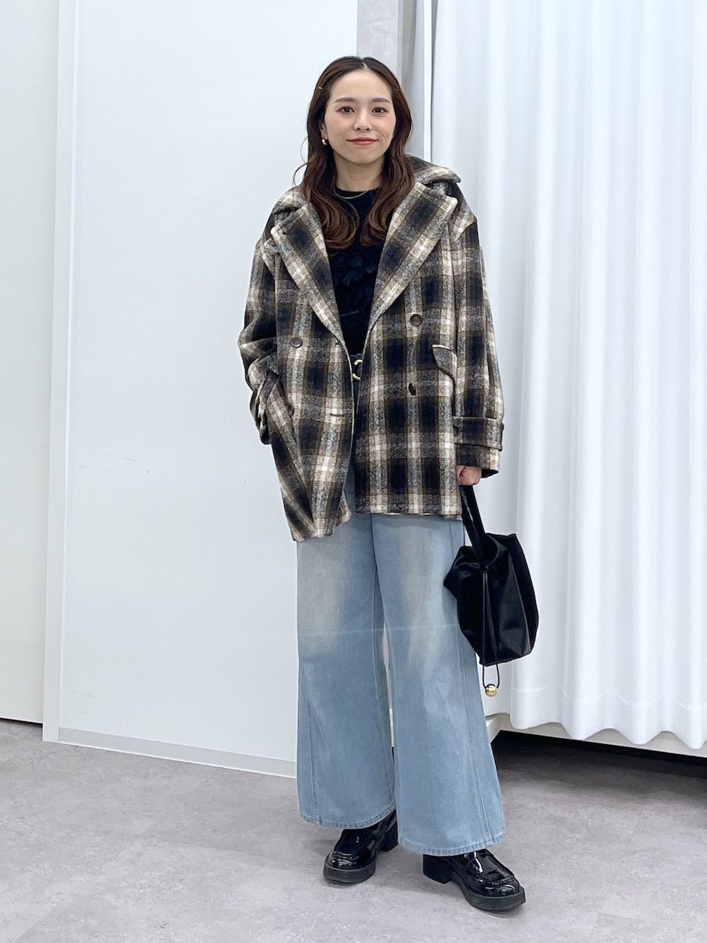 ブラック系のショルダーバッグ、ブルー系のデニムパンツ、ブラック系のニット/セーターを着用したレディースの冬コーディネートの3枚目の写真