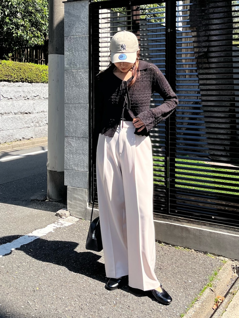 ブラック系のニット/セーター、ベージュ系のスラックス、ブラック系のパンプスを着用したレディースの春コーディネートの2枚目の写真