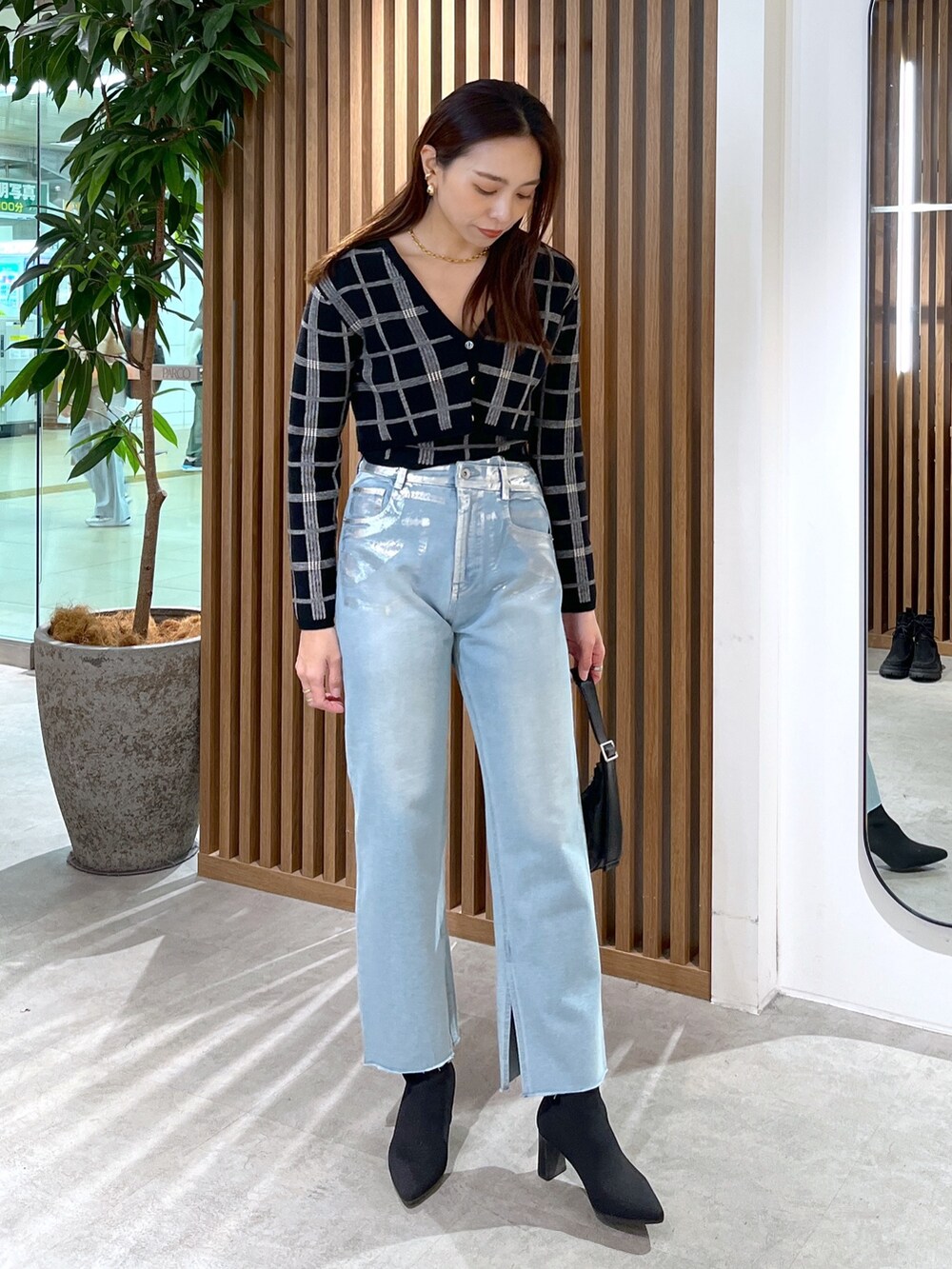 ブルー系のデニムパンツ、ブラック系のニット/セーター、ブラック系のショルダーバッグを着用したレディースの冬コーディネートの9枚目の写真