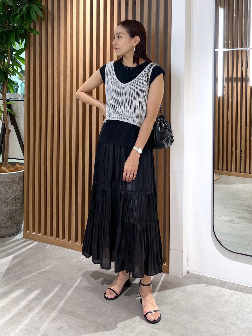 ブラック系のサンダル、ブラック系のスカート、ブラック系のショルダーバッグを着用したレディースの夏コーディネートの2枚目の写真