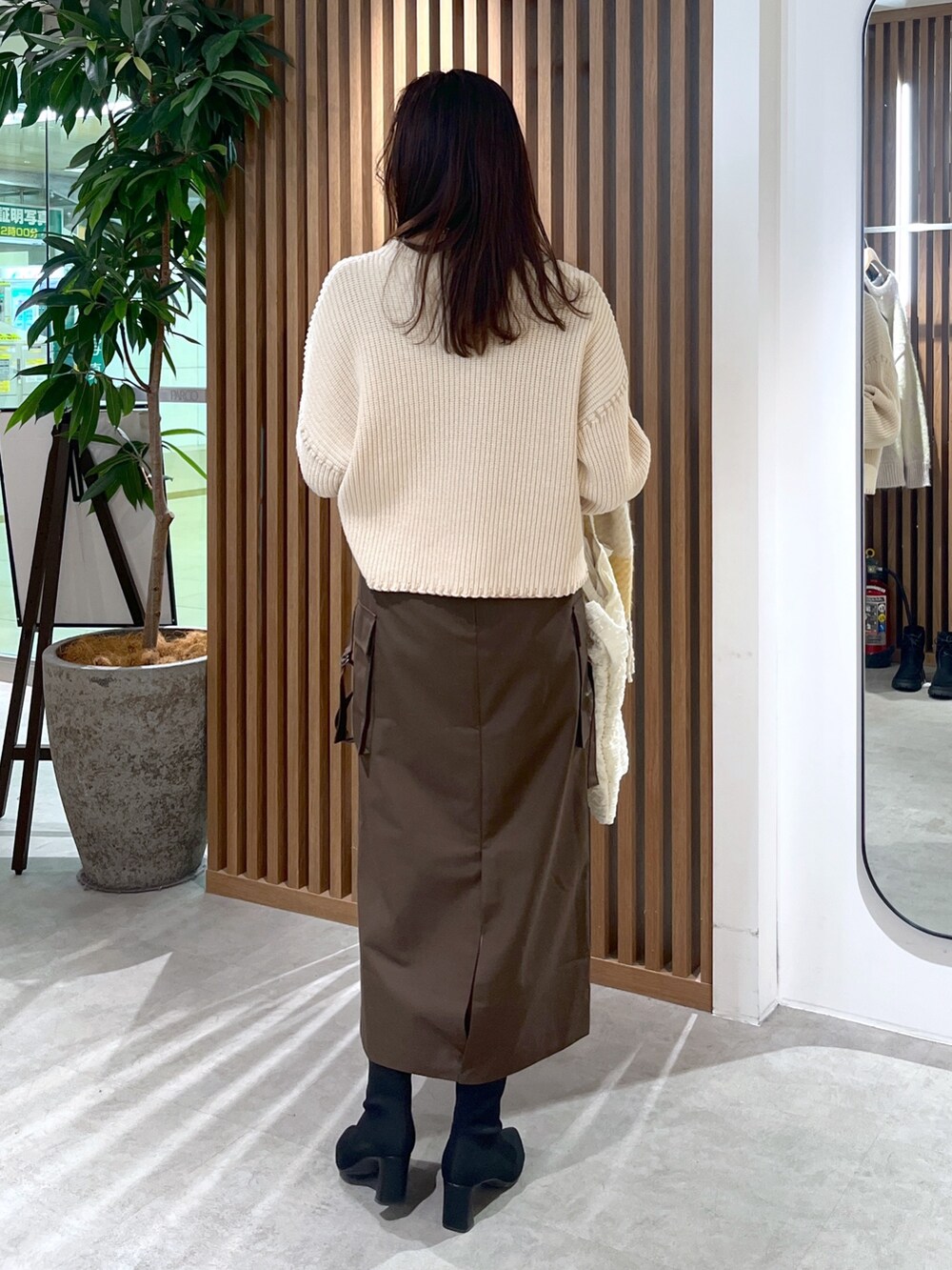 ブラウン系のスカート、ホワイト系のトートバッグ、ホワイト系のニット/セーターを着用したレディースの冬コーディネートの8枚目の写真
