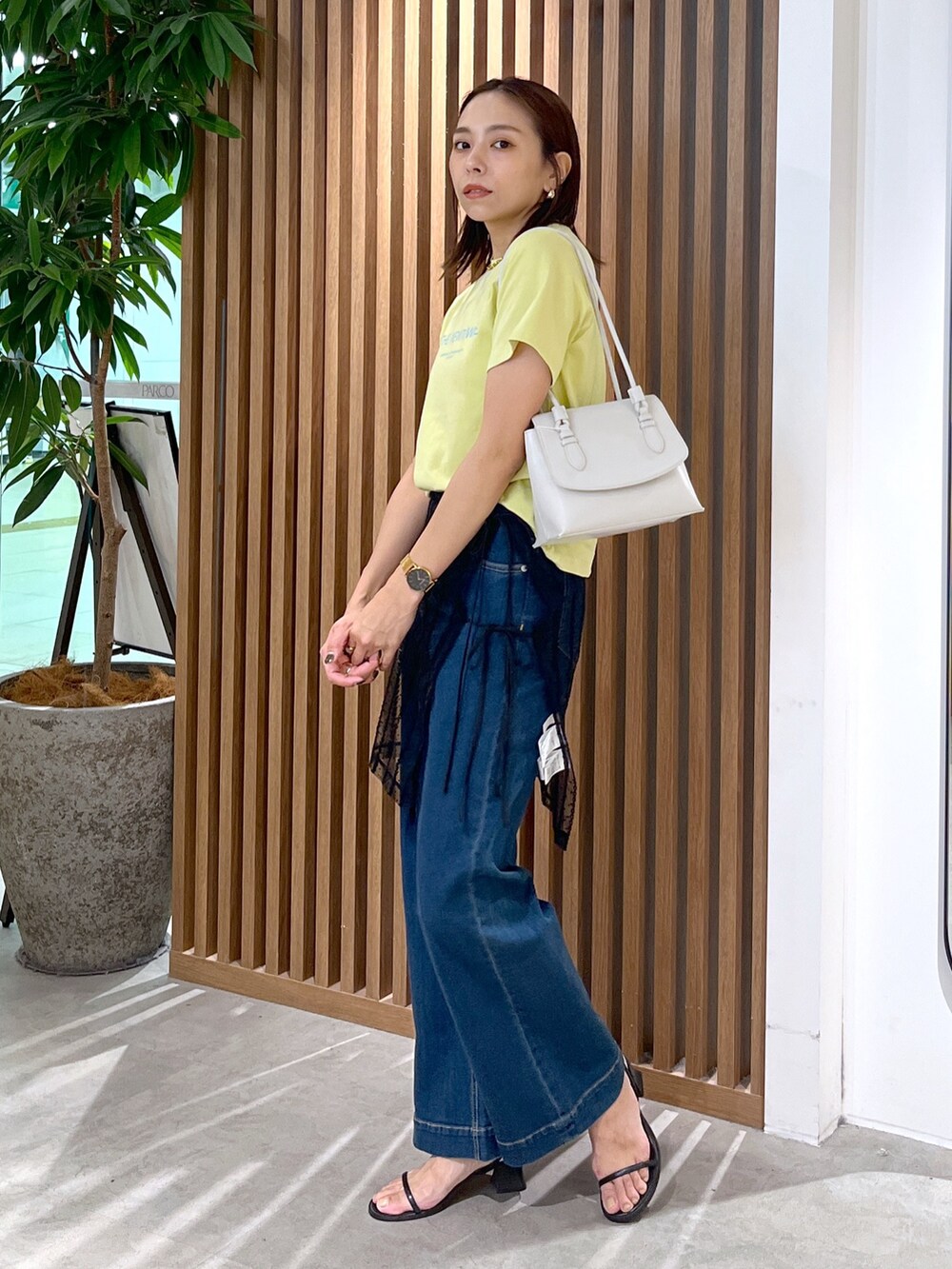 イエロー系のTシャツ/カットソー、ホワイト系のショルダーバッグ、ブラック系のスカートを着用したレディースの夏コーディネートの7枚目の写真