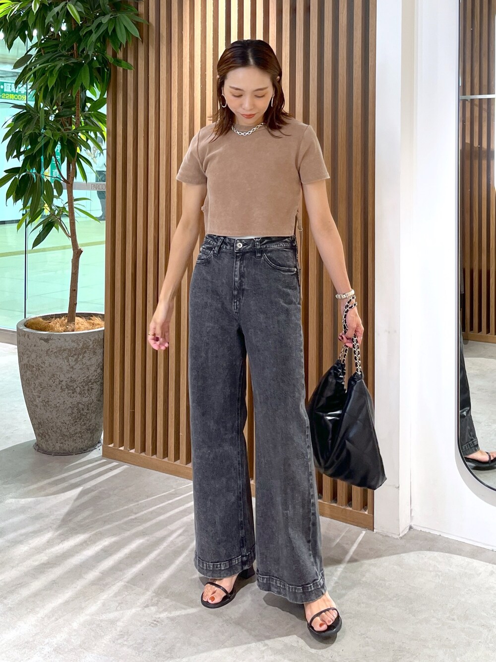 ブラウン系のTシャツ/カットソー、ブラック系のトートバッグ、ブラック系のデニムパンツを着用したレディースの秋コーディネートの2枚目の写真