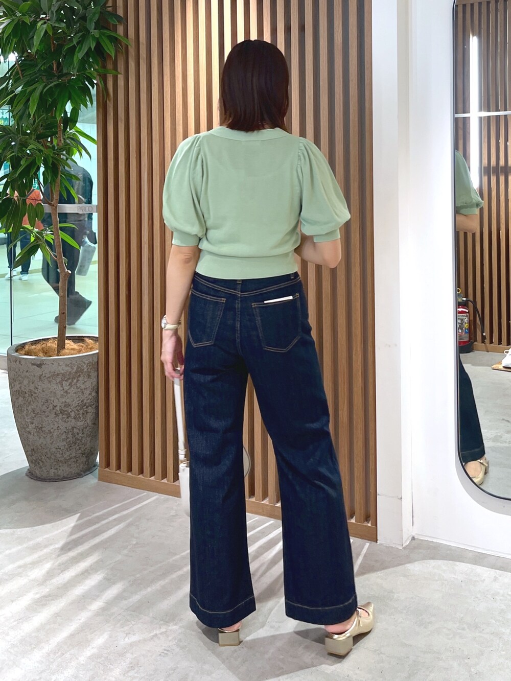 グリーン系のカーディガン/ボレロ、グレー系のショルダーバッグ、ブルー系のデニムパンツを着用したレディースの春コーディネートの5枚目の写真