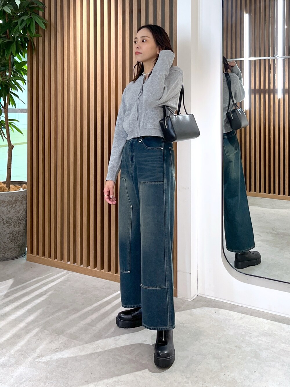 グレー系のワンピース、ブルー系のデニムパンツ、ブラック系のブーツを着用したレディースの冬コーディネートの4枚目の写真