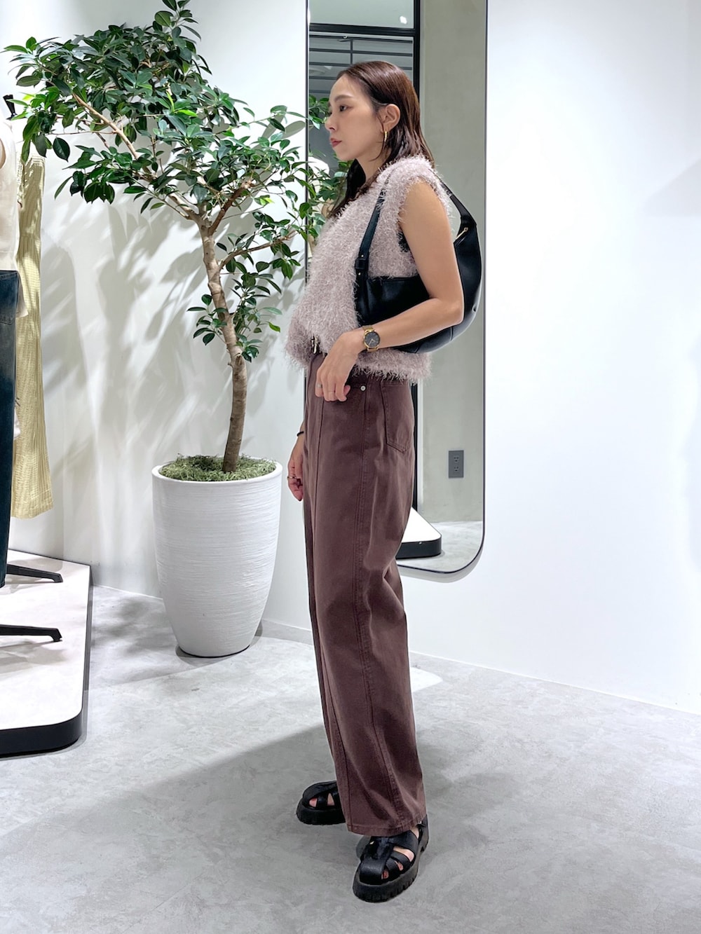 ベージュ系のニット/セーター、ブラック系のハンドバッグ、ブラウン系のデニムパンツを着用したレディースの夏コーディネートの5枚目の写真