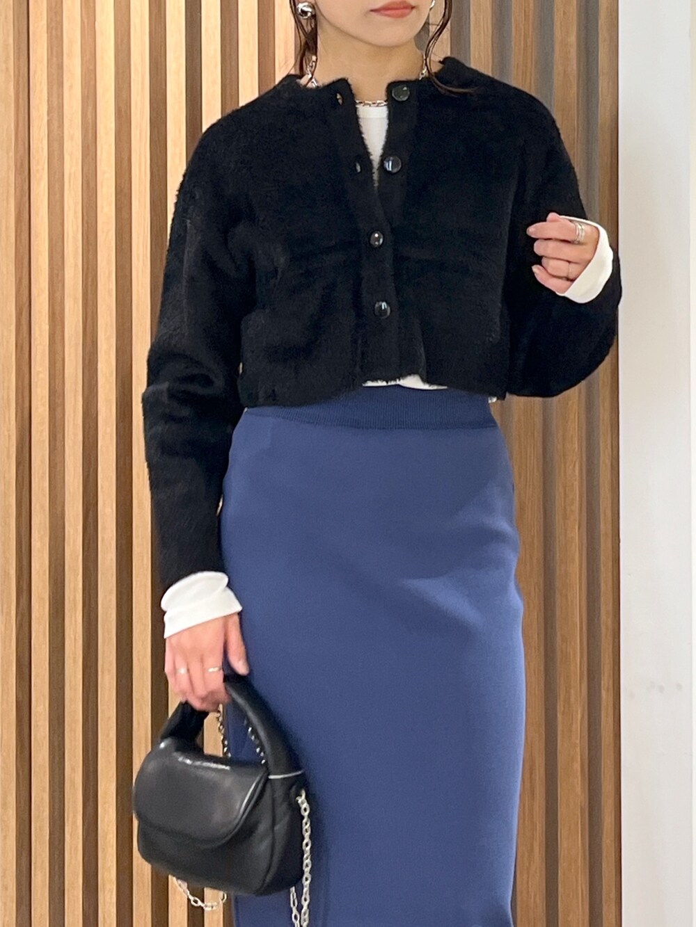 ブラック系のカーディガン/ボレロ、ブラック系のショルダーバッグ、ブルー系のスカートを着用したレディースの冬コーディネートの6枚目の写真