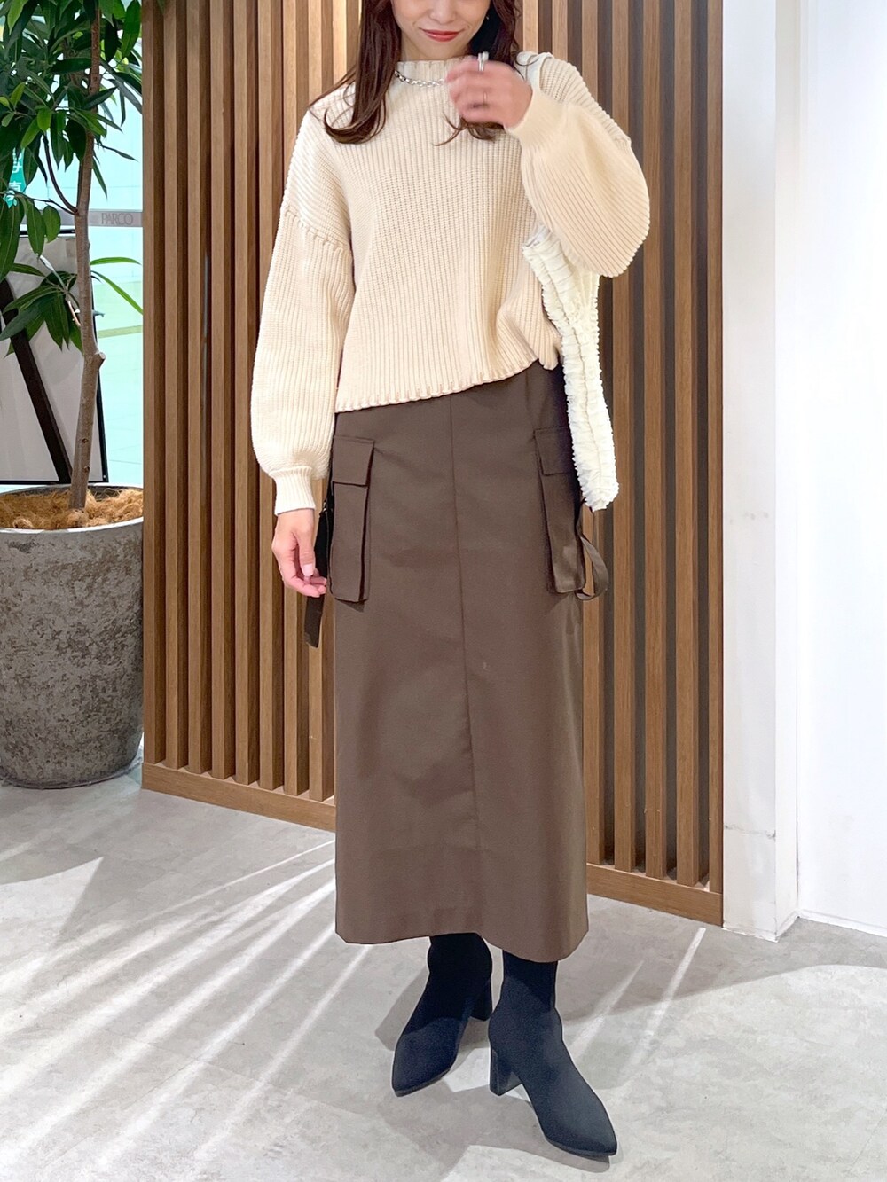 ブラウン系のスカート、ホワイト系のトートバッグ、ホワイト系のニット/セーターを着用したレディースの冬コーディネートの5枚目の写真