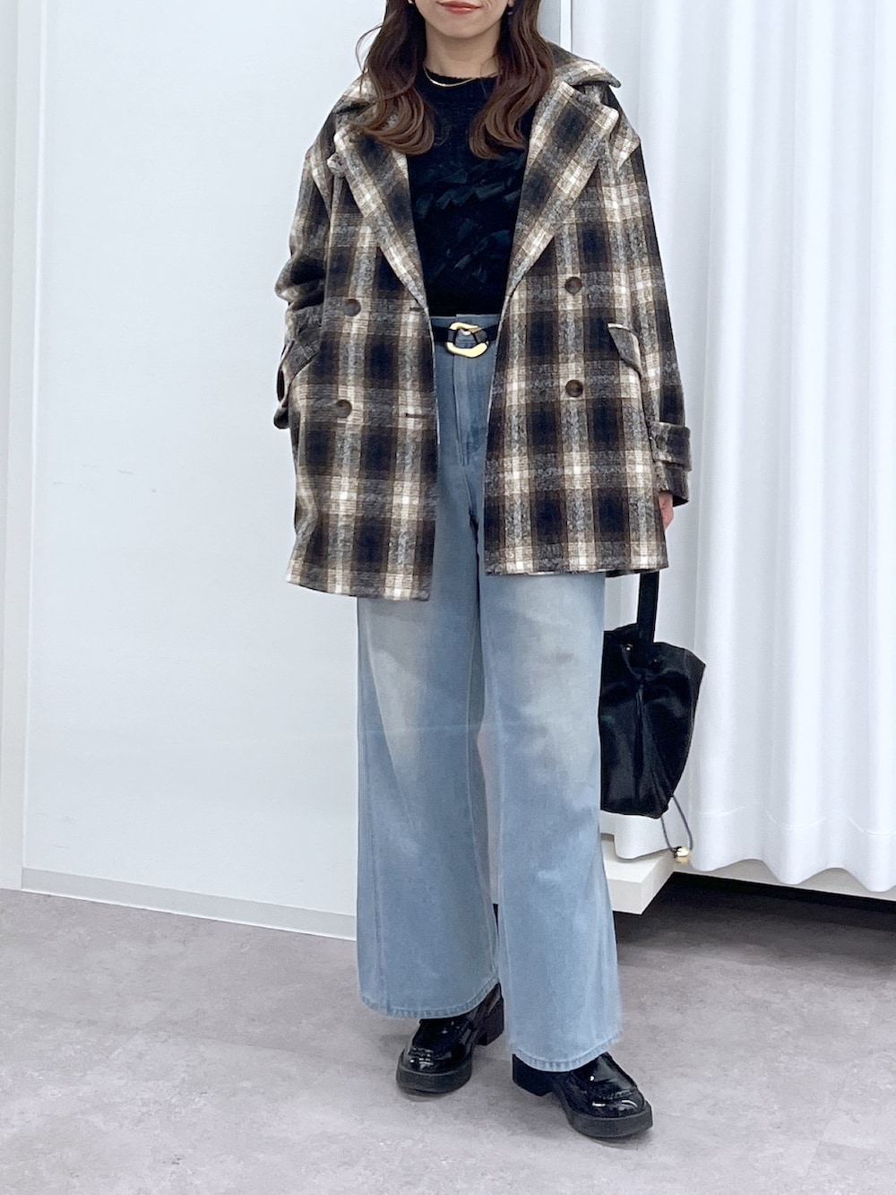 ブラック系のショルダーバッグ、ブルー系のデニムパンツ、ブラック系のニット/セーターを着用したレディースの冬コーディネートの4枚目の写真