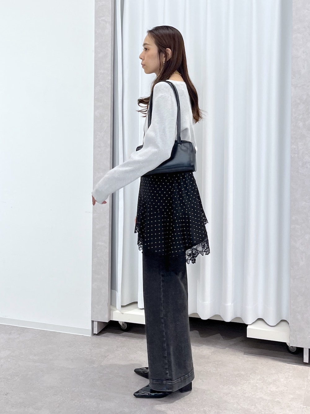 ブラック系のワンピース、ブラック系のデニムパンツ、ブラック系のショルダーバッグを着用したレディースの春コーディネートの3枚目の写真