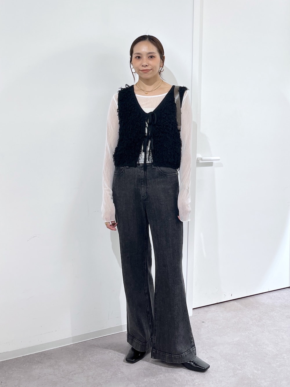 ブラウン系のショルダーバッグ、ブラック系のニット/セーター、ホワイト系のTシャツ/カットソーを着用したレディースの夏コーディネートの3枚目の写真