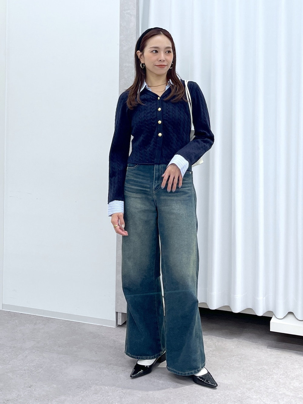 ブラック系のパンプス、ブルー系のニット/セーター、ホワイト系のショルダーバッグを着用したレディースの冬コーディネートの3枚目の写真