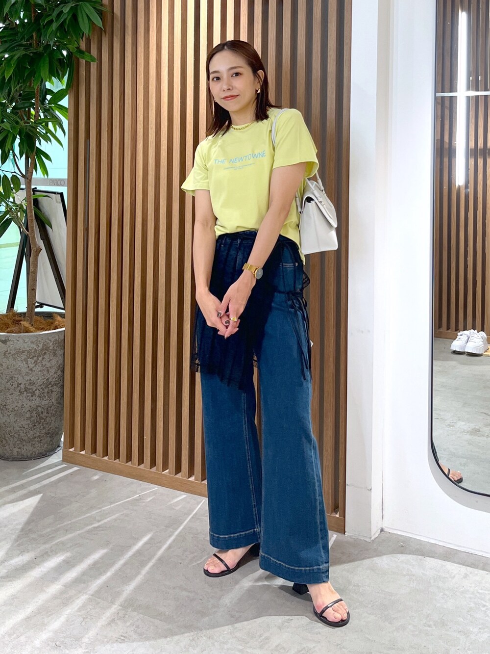 イエロー系のTシャツ/カットソー、ホワイト系のショルダーバッグ、ブラック系のスカートを着用したレディースの夏コーディネートの3枚目の写真