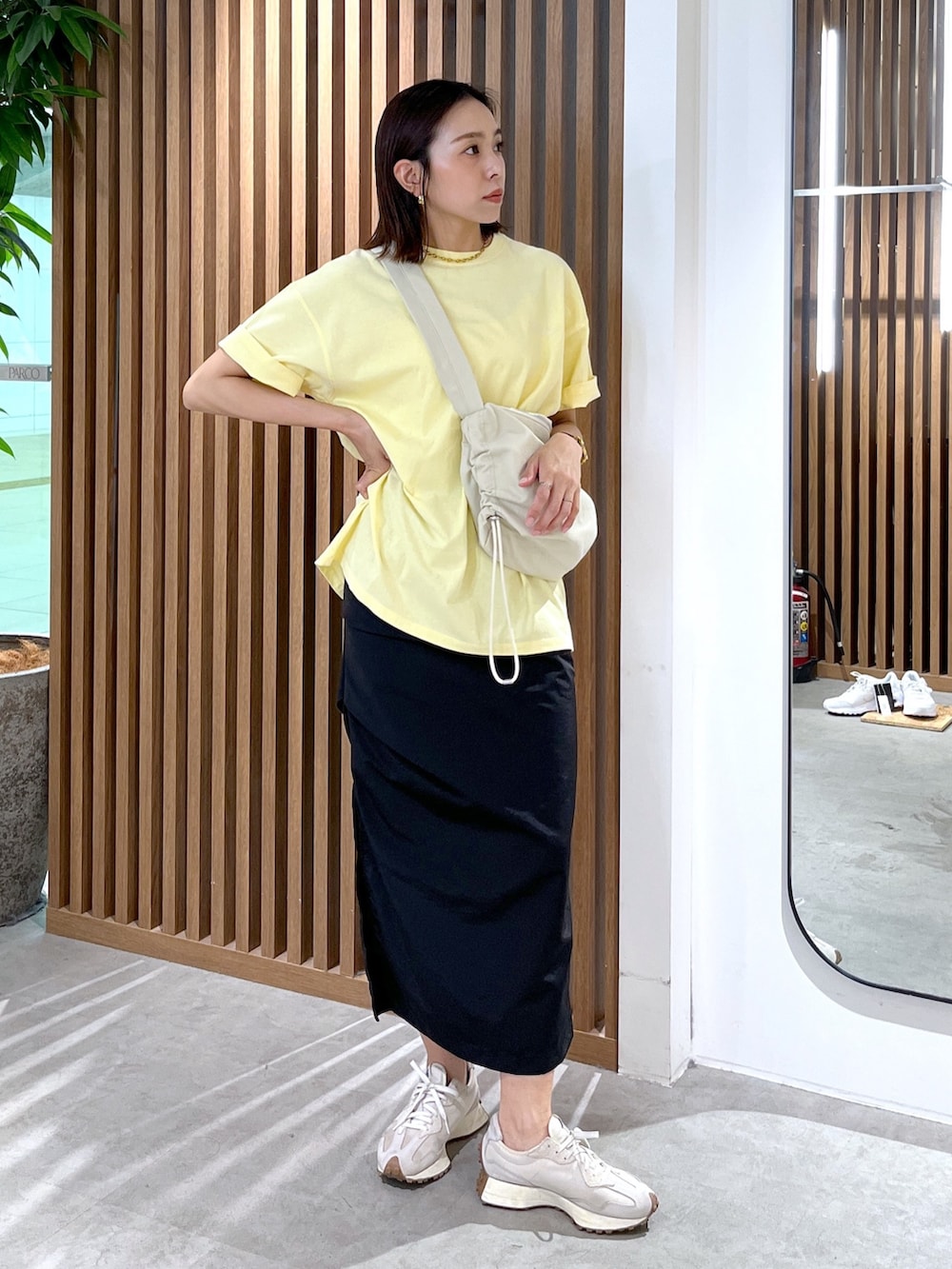 イエロー系のTシャツ/カットソー、ホワイト系のショルダーバッグ、ブラック系のスカートを着用したレディースの春コーディネートの6枚目の写真