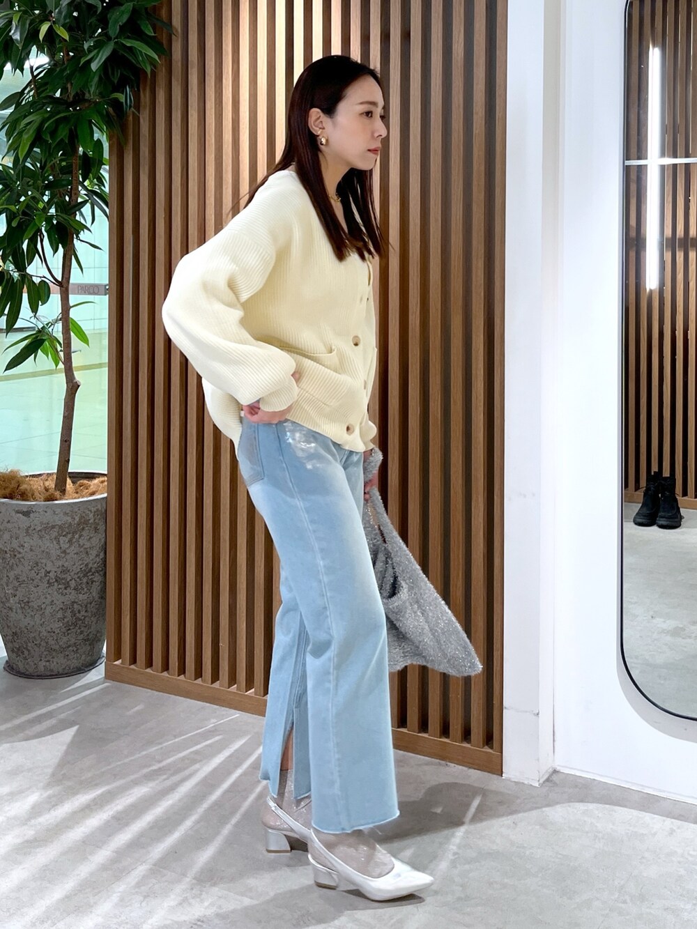 ホワイト系のカーディガン/ボレロ、シルバー系のトートバッグ、ブルー系のデニムパンツを着用したレディースの冬コーディネートの2枚目の写真