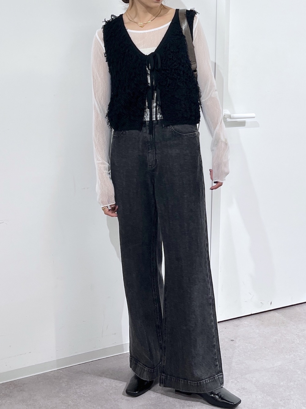 ブラウン系のショルダーバッグ、ブラック系のニット/セーター、ホワイト系のTシャツ/カットソーを着用したレディースの夏コーディネートの6枚目の写真
