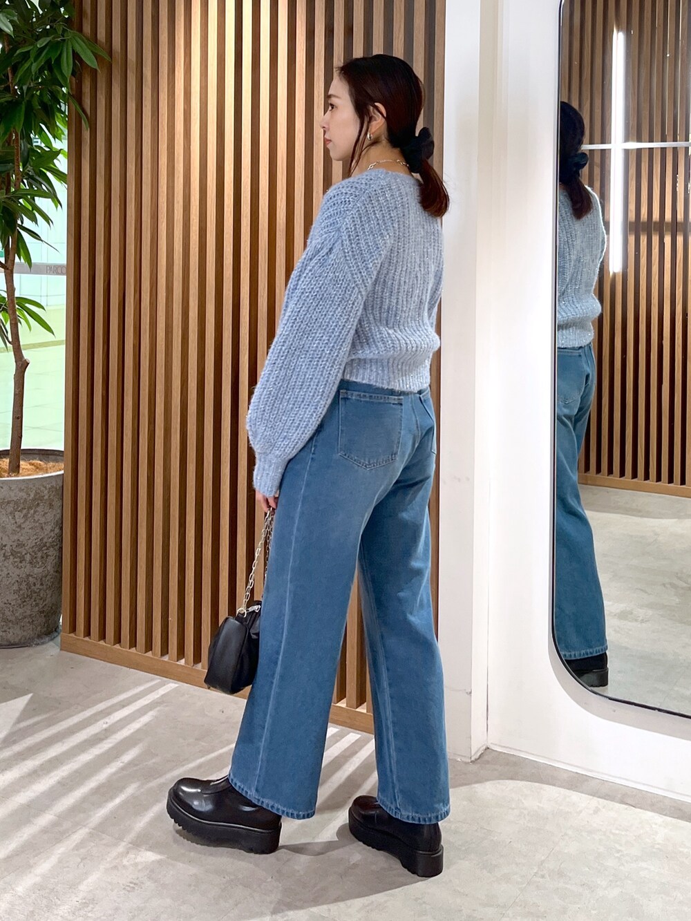 ブルー系のニット/セーター、ブルー系のデニムパンツ、ブラック系のハンドバッグを着用したレディースの冬コーディネートの7枚目の写真