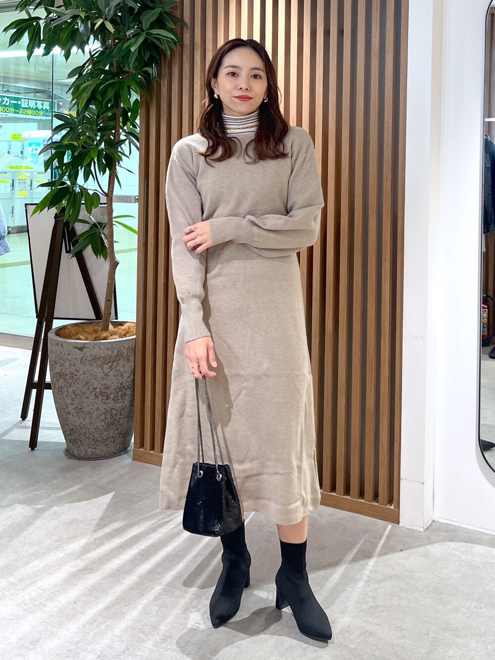ブラック系のショルダーバッグ、ベージュ系のワンピース、ホワイト系のニット/セーターを着用したレディースの冬コーディネートの6枚目の写真