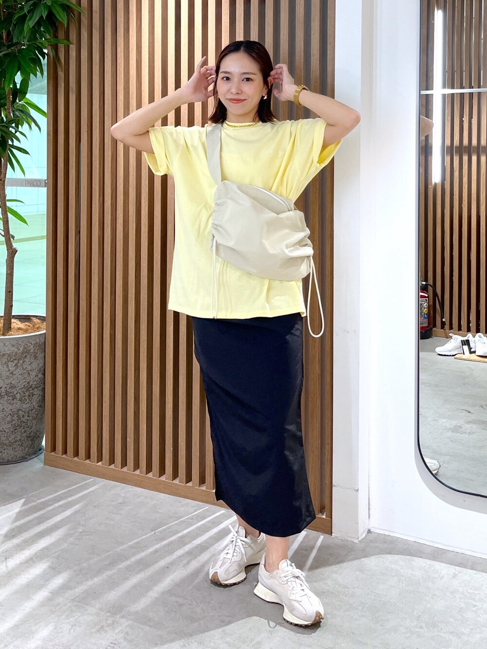 イエロー系のTシャツ/カットソー、ホワイト系のショルダーバッグ、ブラック系のスカートを着用したレディースの春コーディネートの2枚目の写真