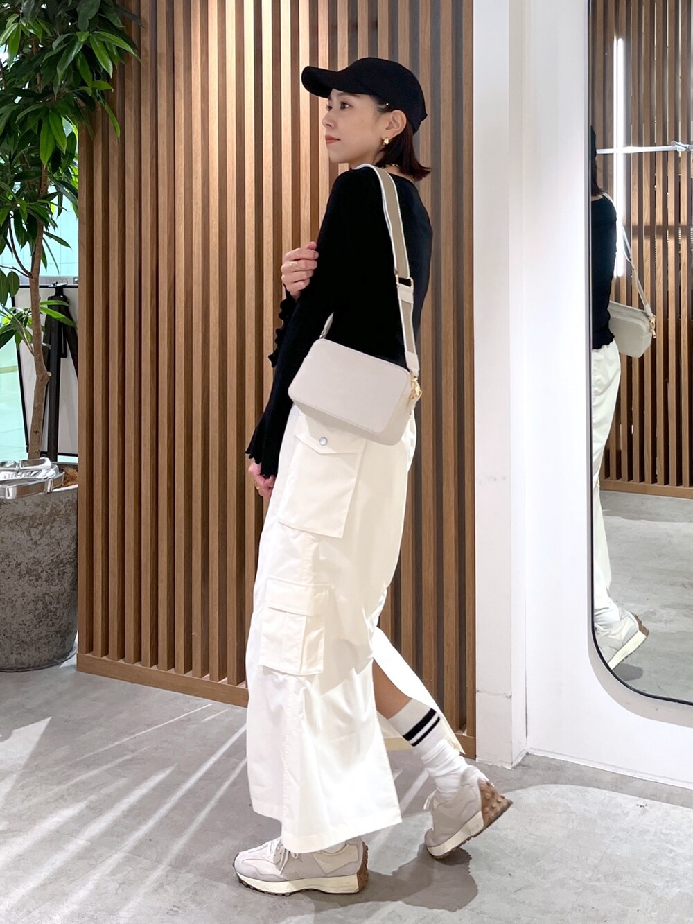 ホワイト系のボディバッグ/ウエストポーチ、ブラック系のトップス、ホワイト系のスカートを着用したレディースの春コーディネートの6枚目の写真