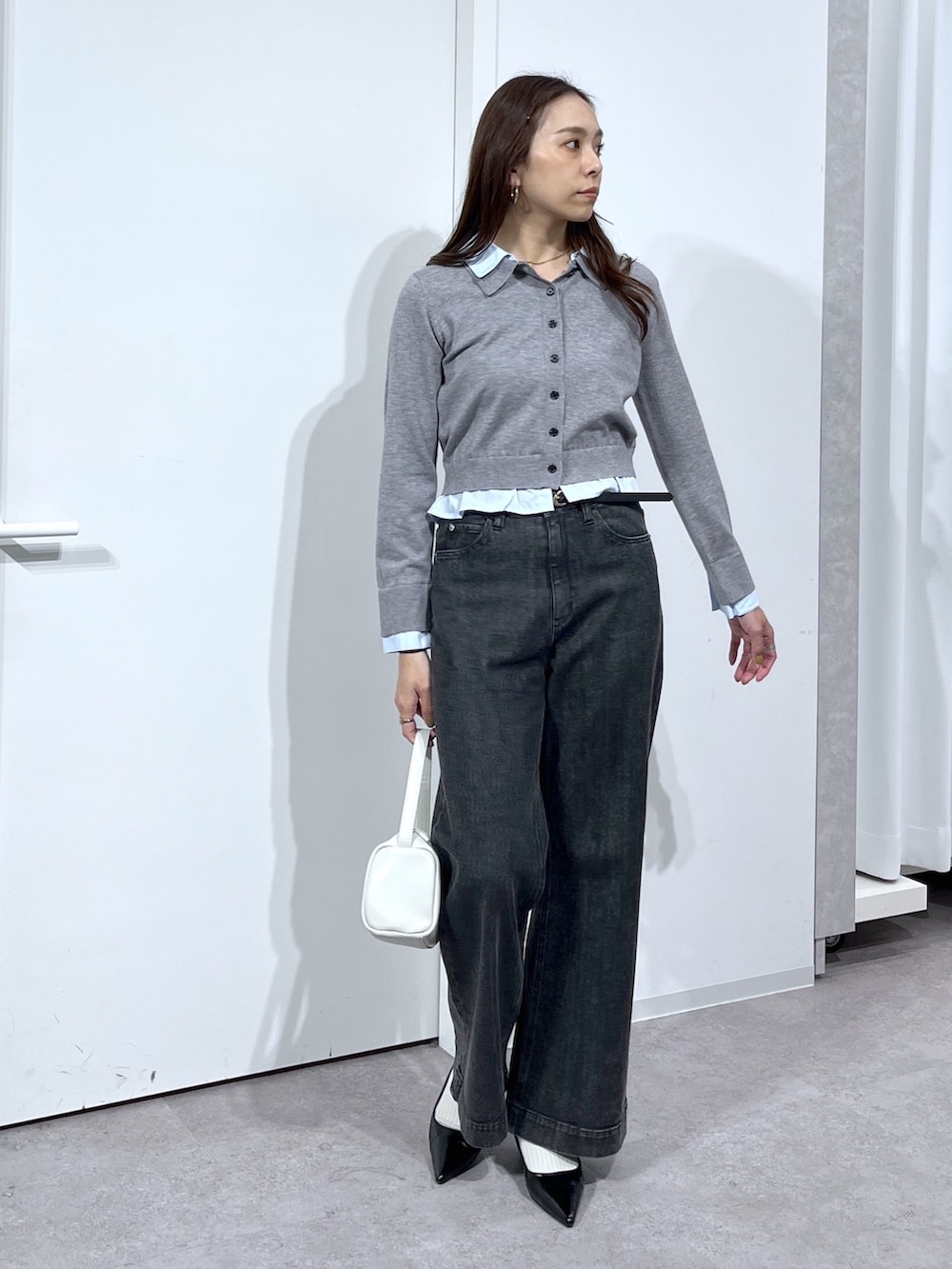 グレー系のニット/セーター、ホワイト系のハンドバッグ、ブラック系のデニムパンツを着用したレディースの春コーディネートの5枚目の写真