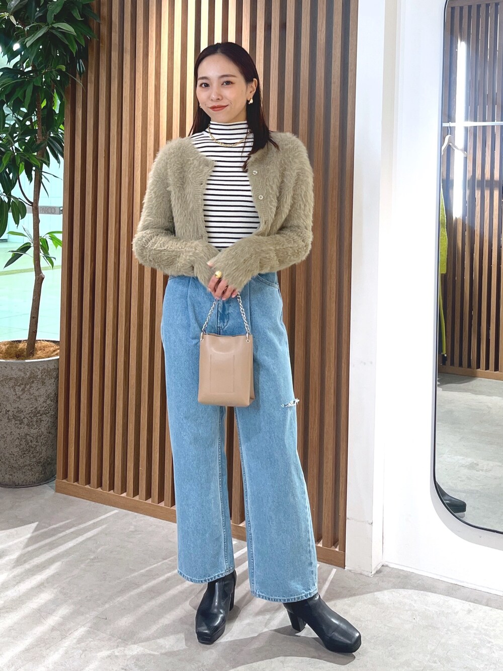 ベージュ系のカーディガン/ボレロ、ブルー系のデニムパンツ、ホワイト系のニット/セーターを着用したレディースの冬コーディネートの4枚目の写真