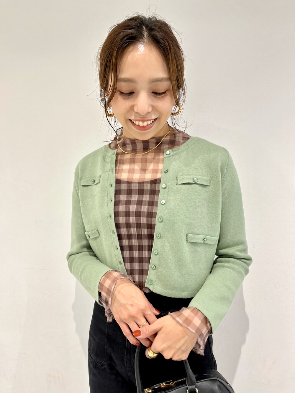 ブラック系のボストンバッグ、グリーン系のカーディガン/ボレロ、ブラウン系のTシャツ/カットソーを着用したレディースの秋コーディネートの3枚目の写真