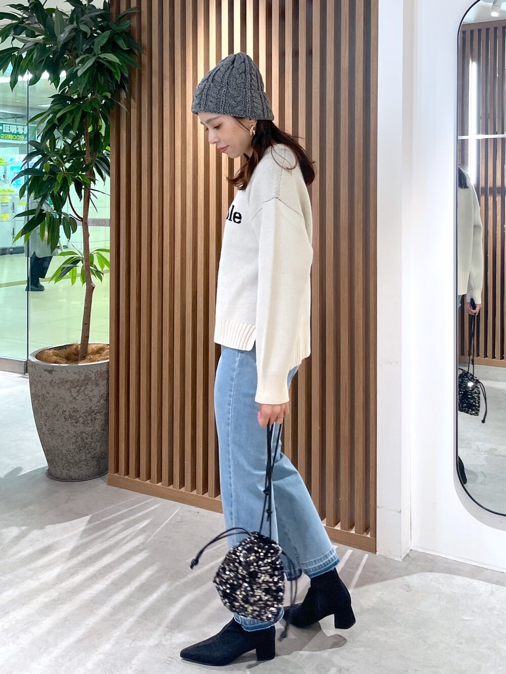 ホワイト系のニット/セーター、ブルー系のデニムパンツ、ブラック系のブーツを着用したレディースの秋コーディネートの3枚目の写真