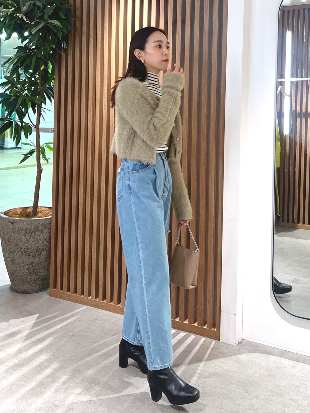 ベージュ系のカーディガン/ボレロ、ブルー系のデニムパンツ、ホワイト系のニット/セーターを着用したレディースの冬コーディネートの3枚目の写真