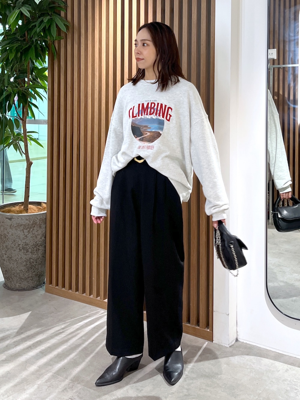 ホワイト系のスウェット、ブラック系のショルダーバッグ、ブラック系のスラックスを着用したレディースの秋コーディネートの9枚目の写真