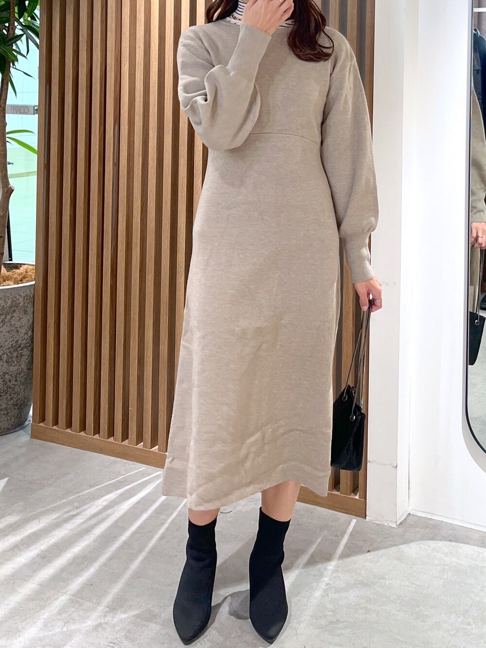 ブラック系のショルダーバッグ、ベージュ系のワンピース、ホワイト系のニット/セーターを着用したレディースの冬コーディネートの5枚目の写真